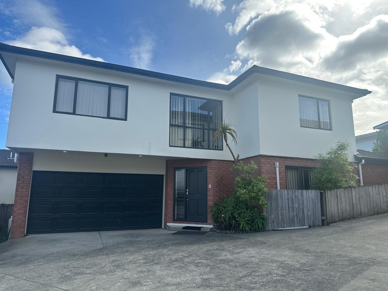 The white and brick exterior of Samzh Homestay beneath a blue New Zealand sky